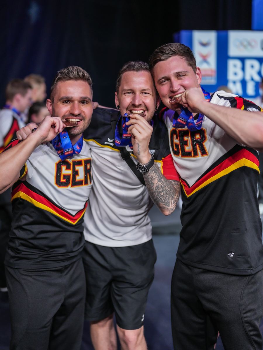 Vincent and two teammates biting their bronze medals at the ICU World Championships 2026